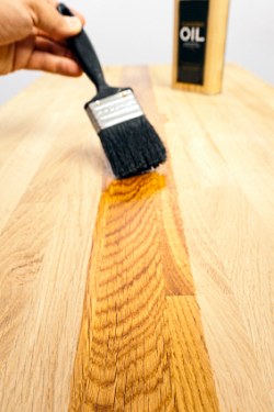 Applying tung oil to a wood kitchen countertop using a brush.