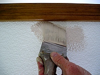 Using a brush to cut-in the wall to the trim.