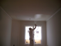 Spraying paint on interior ceiling.