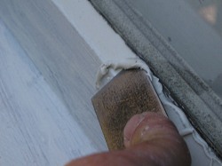 Smoothing glazing compound with a putty knife.