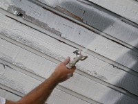 Using an airless paint sprayer to prime rough sawn lumber siding.