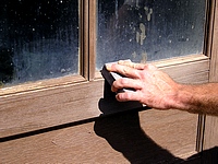 Hand sanding stained windows with a medium/fine sanding sponge.