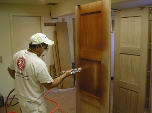 Spraying wood stain on doors using an HVLP sprayer.
