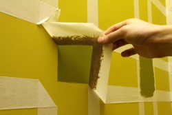 Painting squares on a wall- removing the making tape to reveal the pattern.