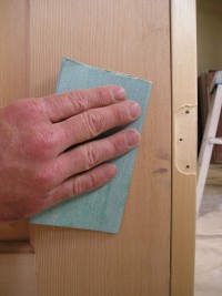 Removing a blemish on a solid wood interior door by hand sanding.