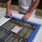 Masking a window before spraying a steel door.